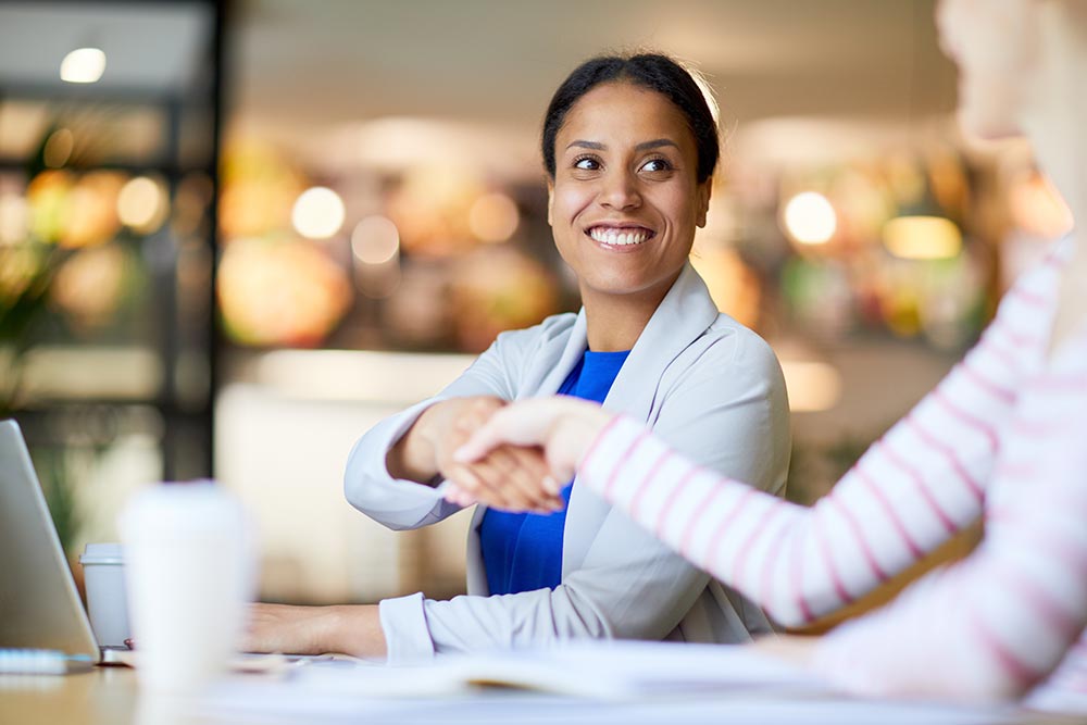 Two people shaking hands in a coffee shop