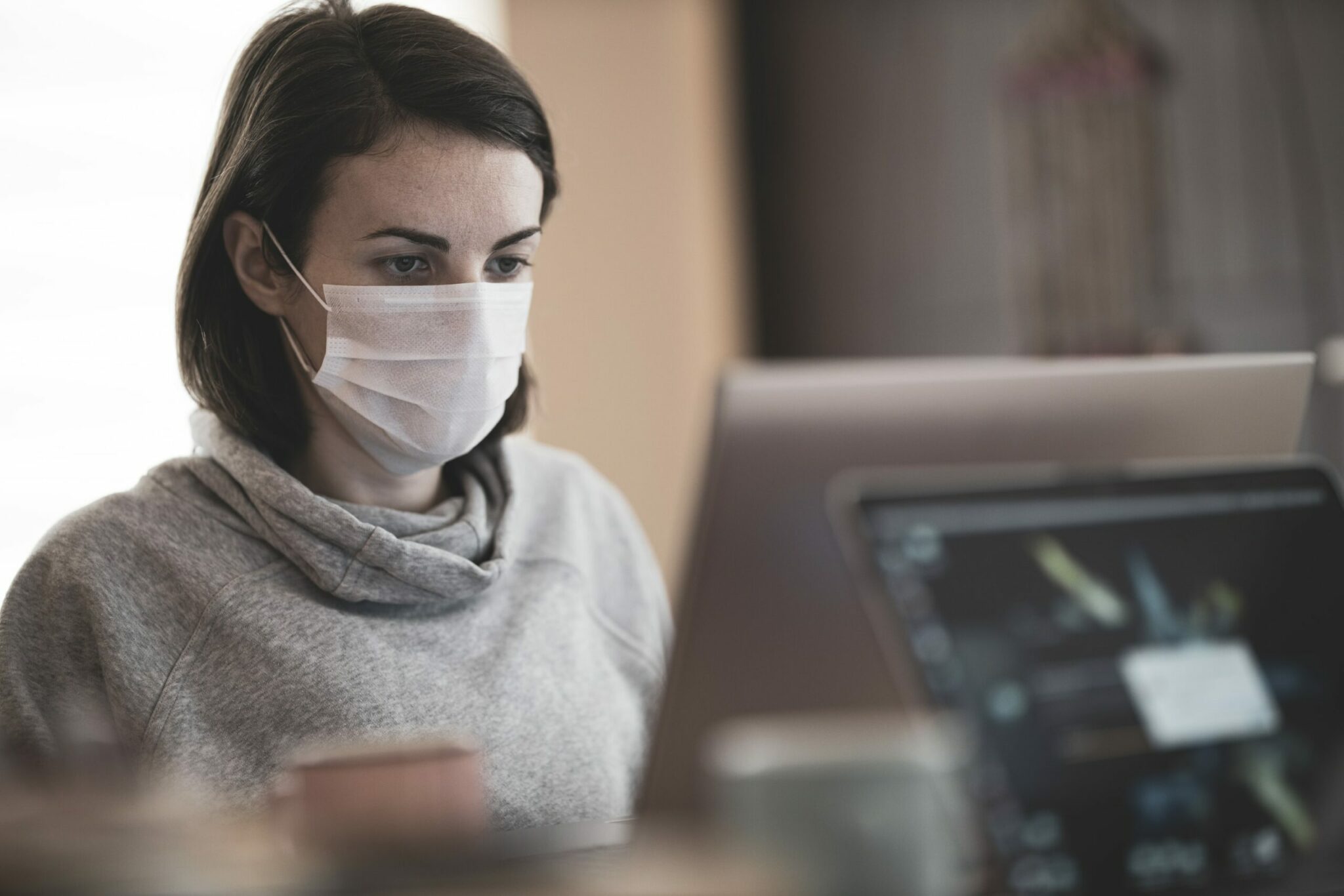 woman in an office wearing a mask works at her computer