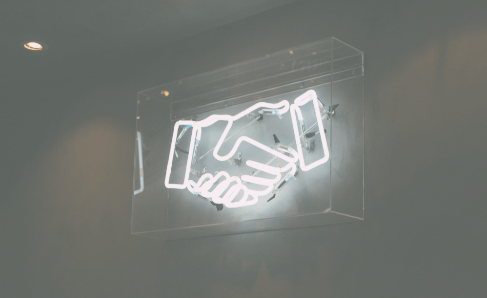 neon sign of handshake up on dark wall in workplace