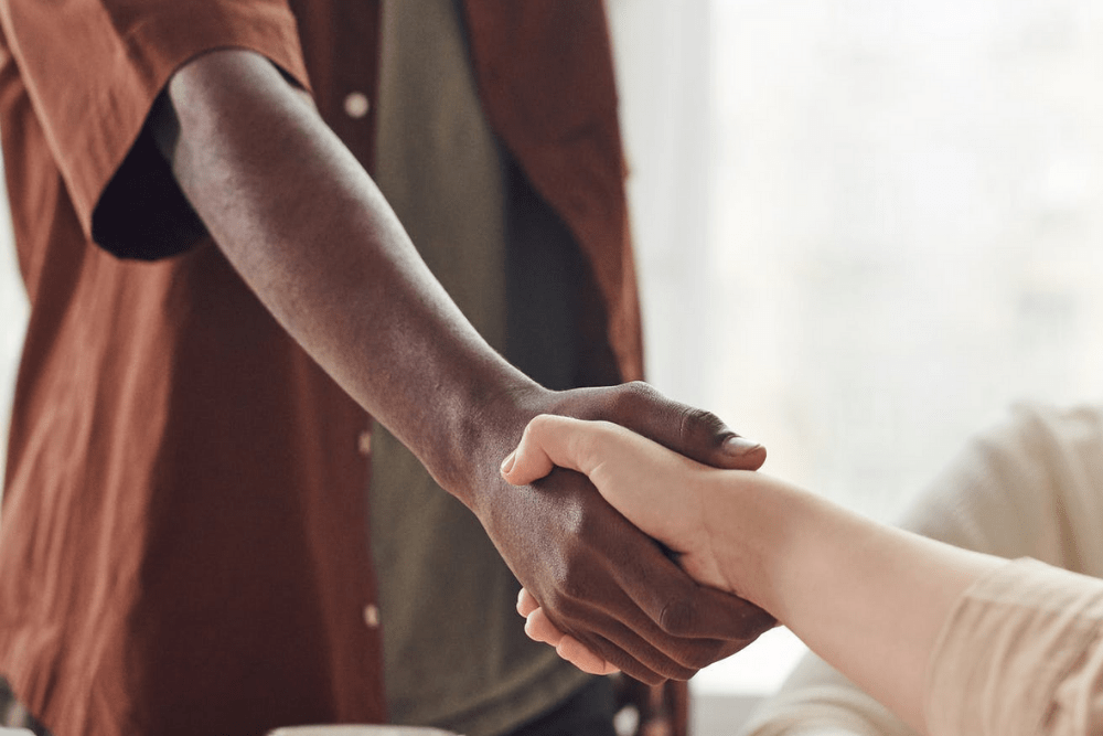 black coworker shakes white coworker's hand in the office