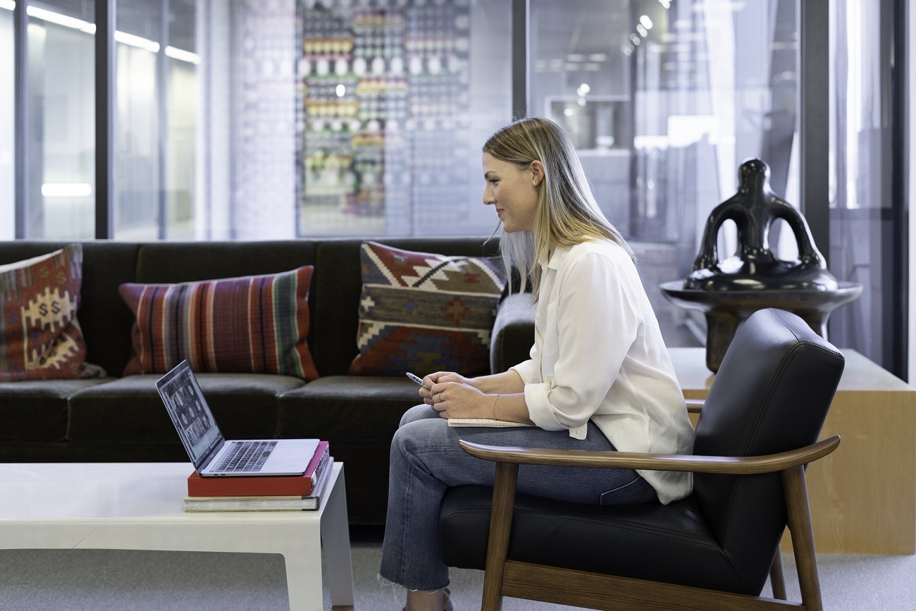 woman sits in office space speaking on a video call