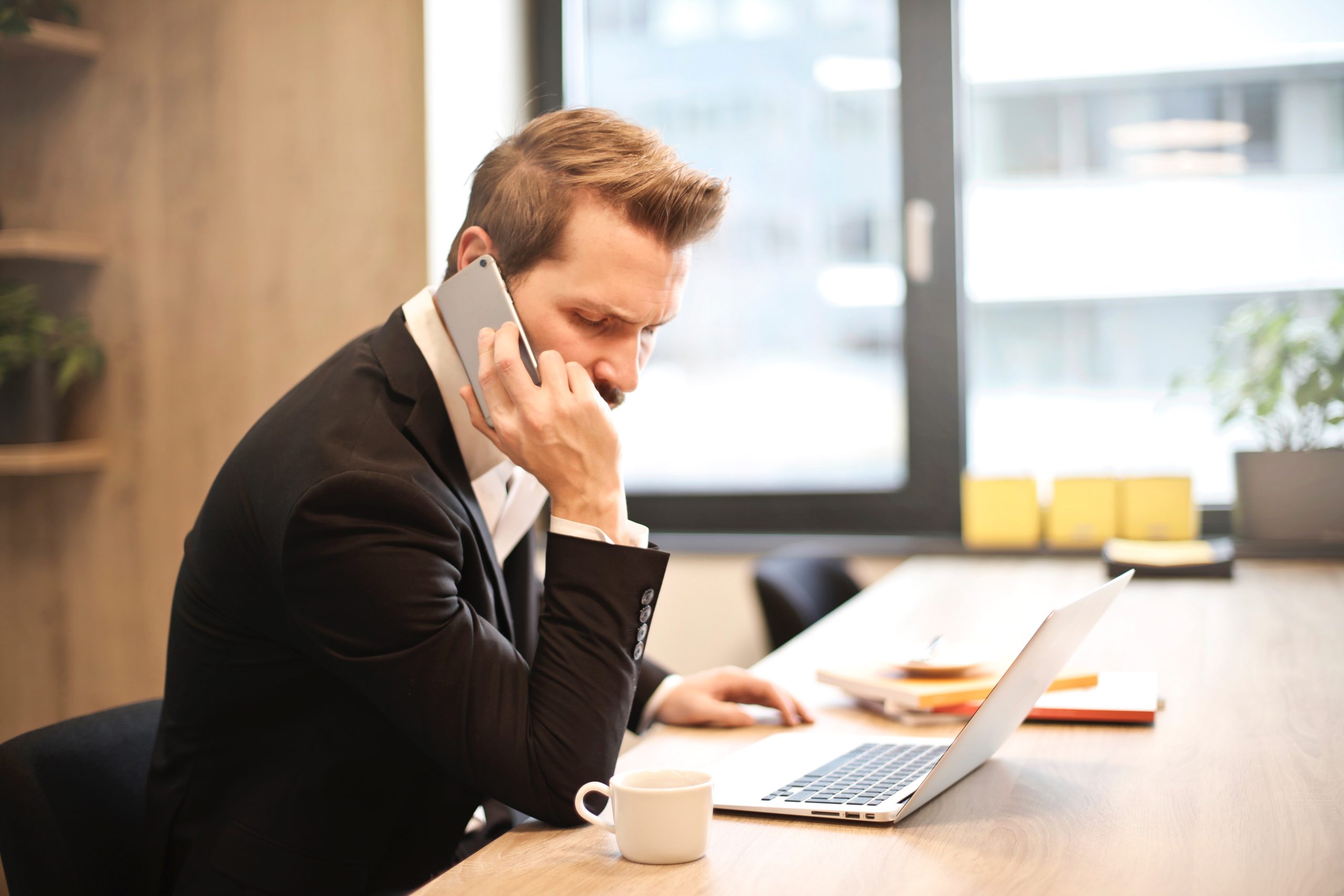 Man in the office speaking on the phone with a stressed look on his face