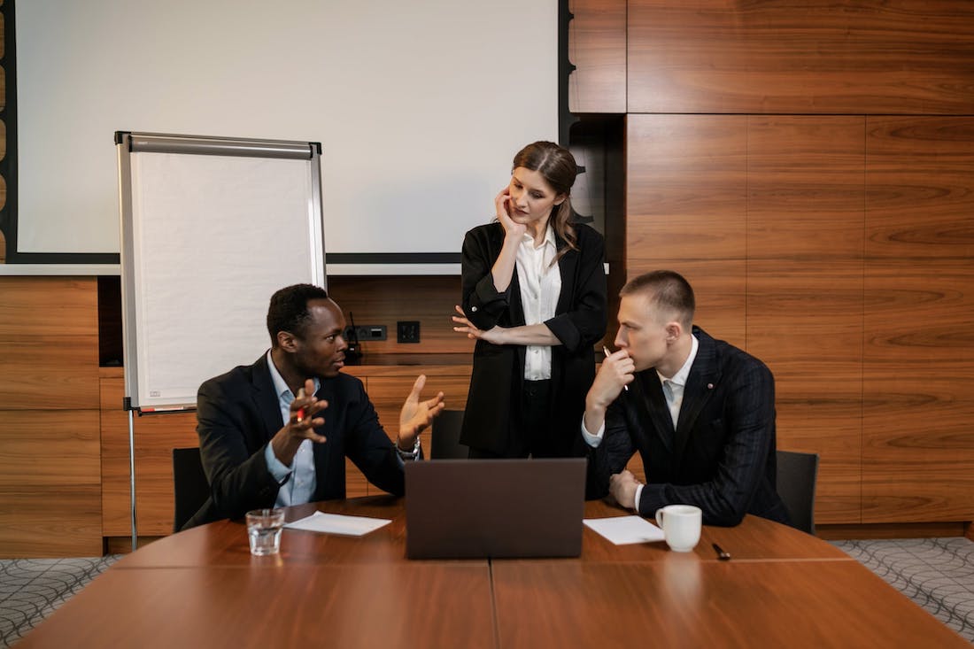 Three employees in a meeting in a professional workplace boardroom