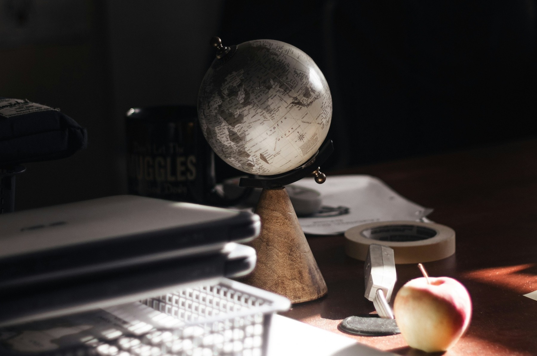 Dark image of an office desk with a miniature globe on it