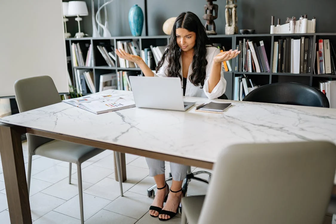 Brunet woman sits confused at her desk at work