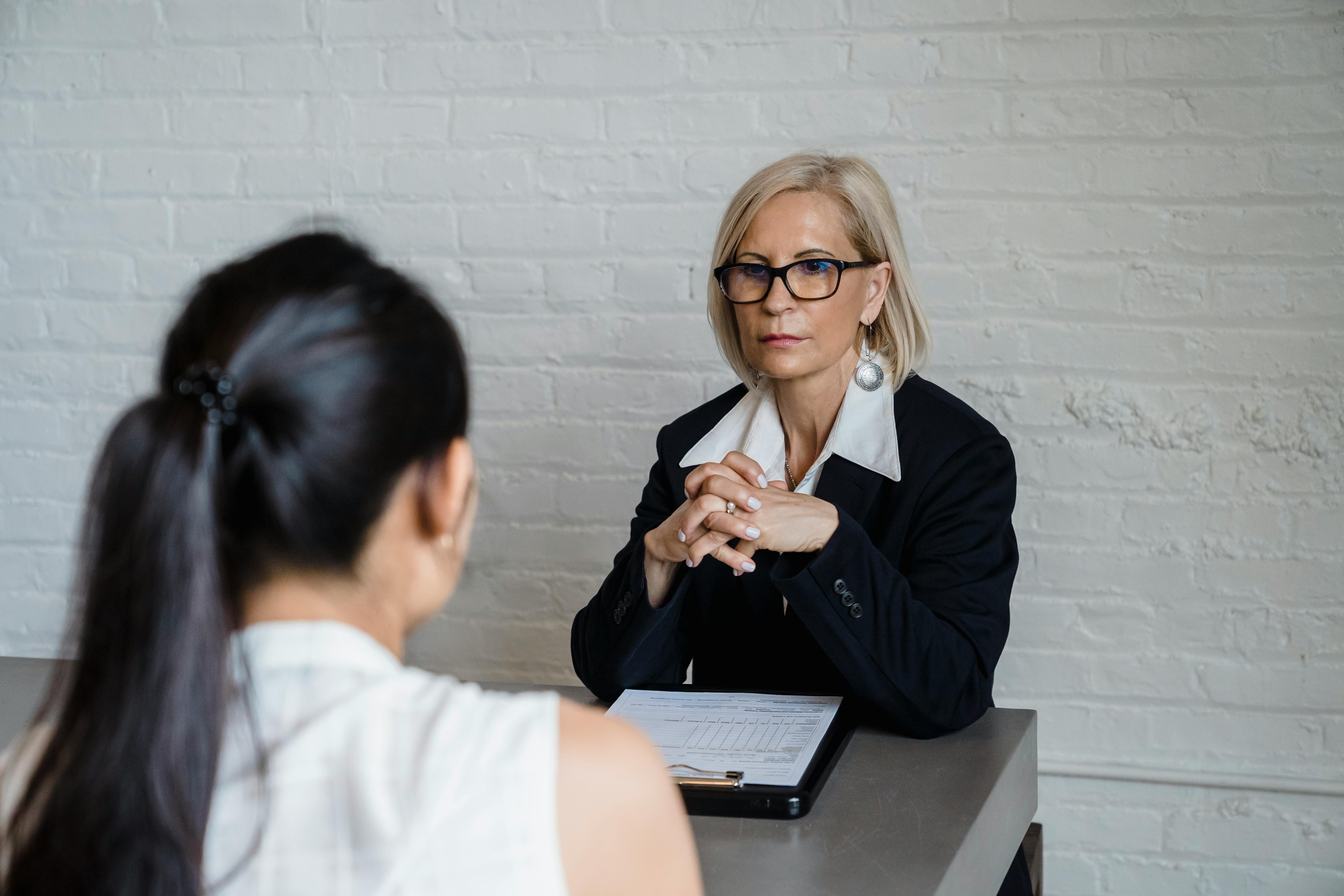 an employer and employee sit in a serious setting in the office